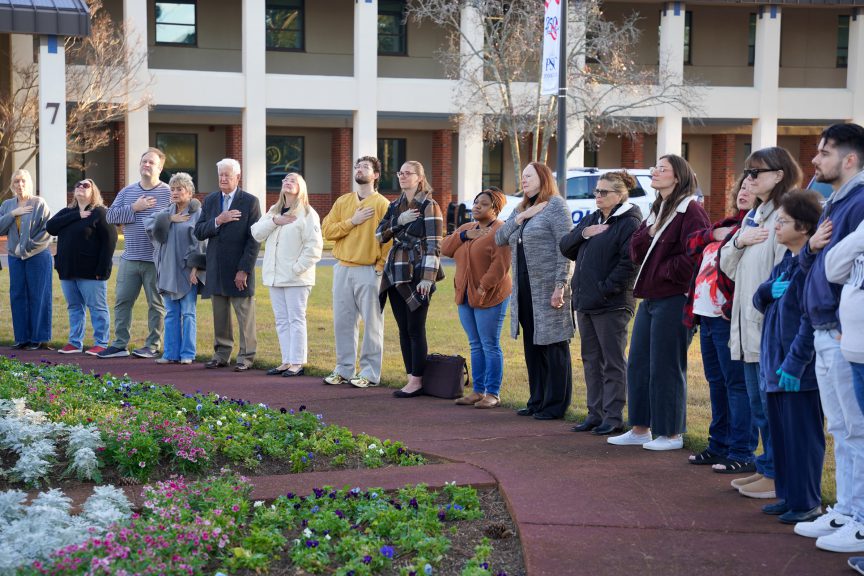 PSC staff gather for the Pledge of Allegiance at the flagpole on the Pensacola campus.